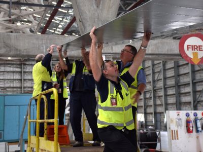 The team holds the left aileron in position for reattachment. Judging by the expression on Dan's face, this requires fierce concentration. Nov 2016.